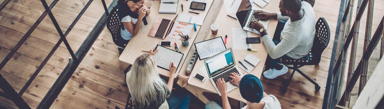 Diverse groep mensen die in een kantoorsituatie op computers werkt aan een creatieve oplossing