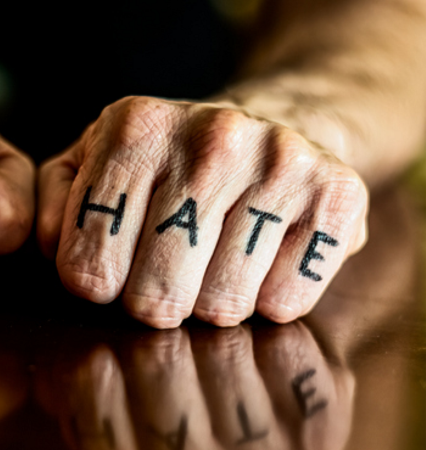 Foto van een gebalde vuist met daarop met viltstift het woord HATE getekend