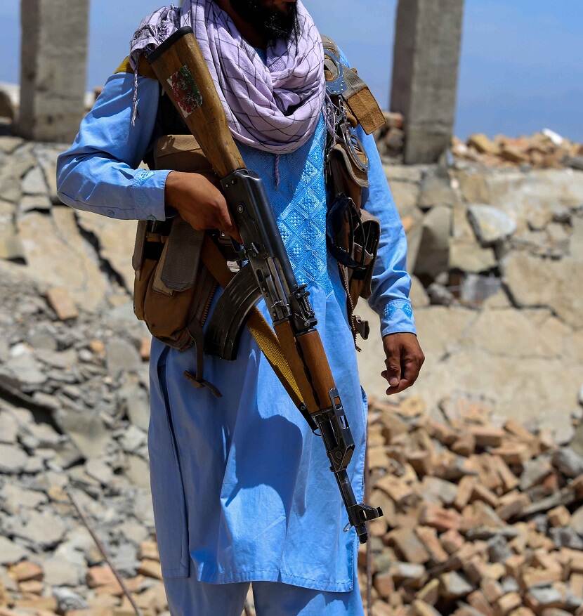 Foto van een Talibanstrijder bij een vernietigd explosievendepot van ISIS in Afghanistan